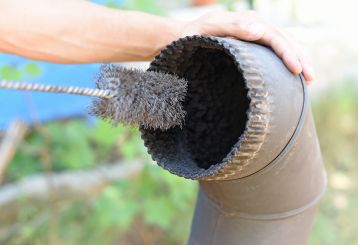 Professional chimney cleaner inspecting and removing creosote buildup