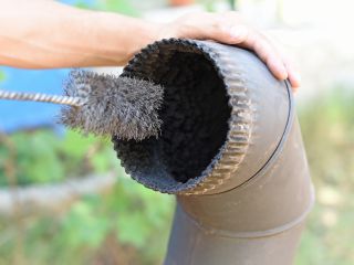 Professional chimney cleaner inspecting and removing creosote buildup